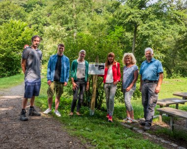 Mehrere Personen stehen an einer der neuen Tafeln, die am Wegesrand des Gelbachtrails informieren.